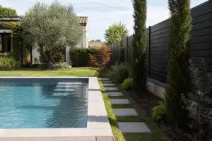 Piscine rectangulaire bordée de dalles et jardin