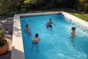 Quatre personnes discutent dans une piscine extérieure